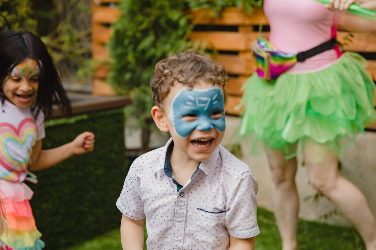 services-01 Children having fun with face painting at a lively outdoor birthday party.